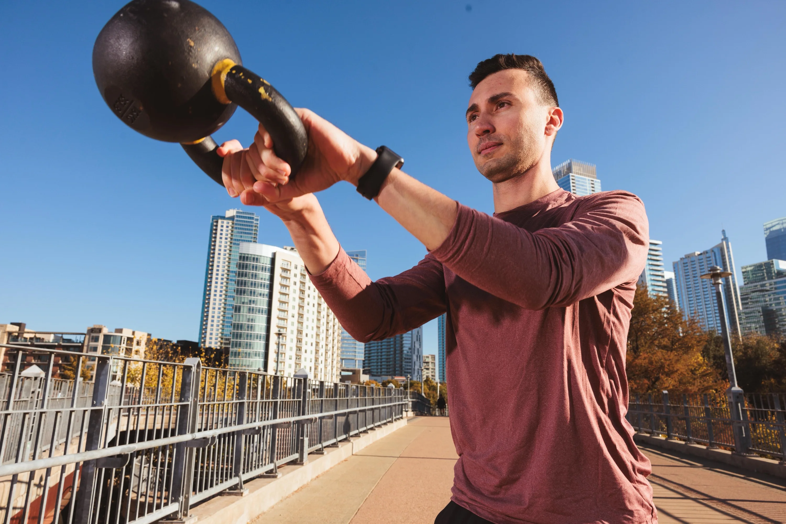 Athlete performing a kettlebell swing against an urban skyline